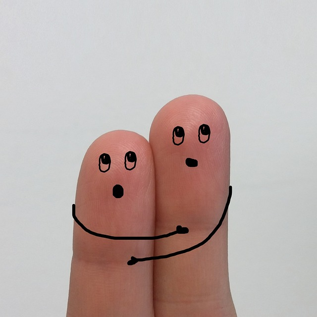dois dedos juntos com uma carinha e dois braços se abraçando desenhados neles.