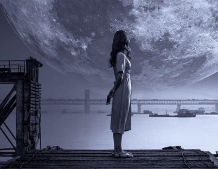 mulher em cena noturna, na beira do cais olhando o mar, uma ponte ao longe e uma enorme lua cheia.